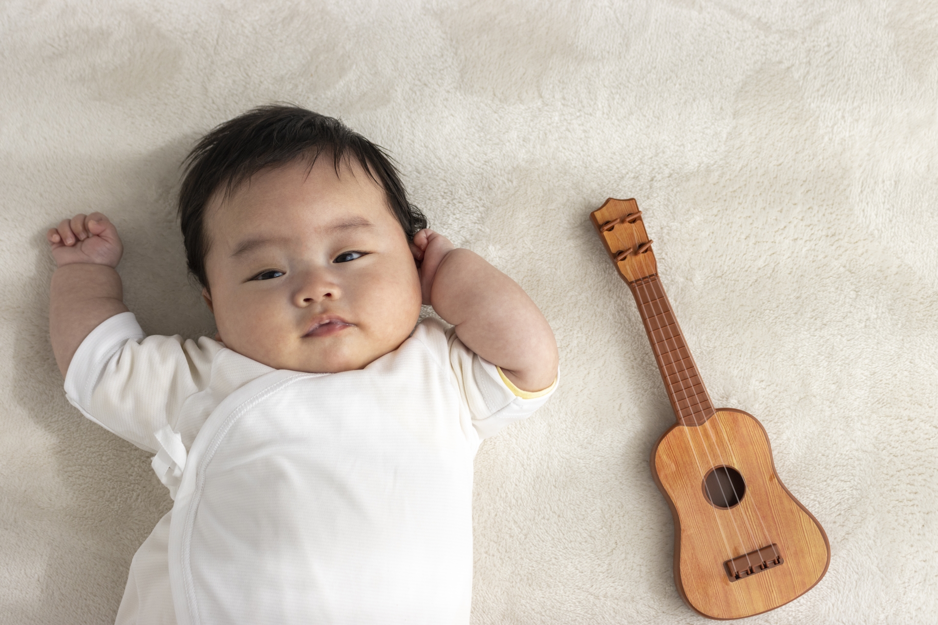 起きている赤ちゃんと玩具のギター